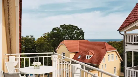 Balkon mit Tisch vor einem Haus umgeben von Bäumen.