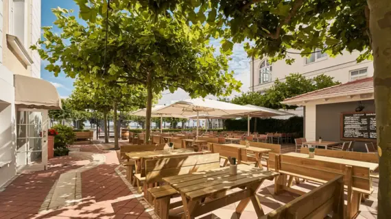 Ein Biergarten mit vielen Holzbänken und Tischen mit Blick auf die Ostsee. 