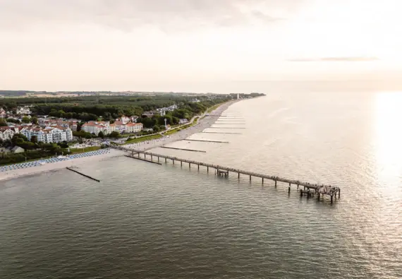 Langer Steg führt zu einem Strand mit klarem Himmel und ruhigem Wasser.