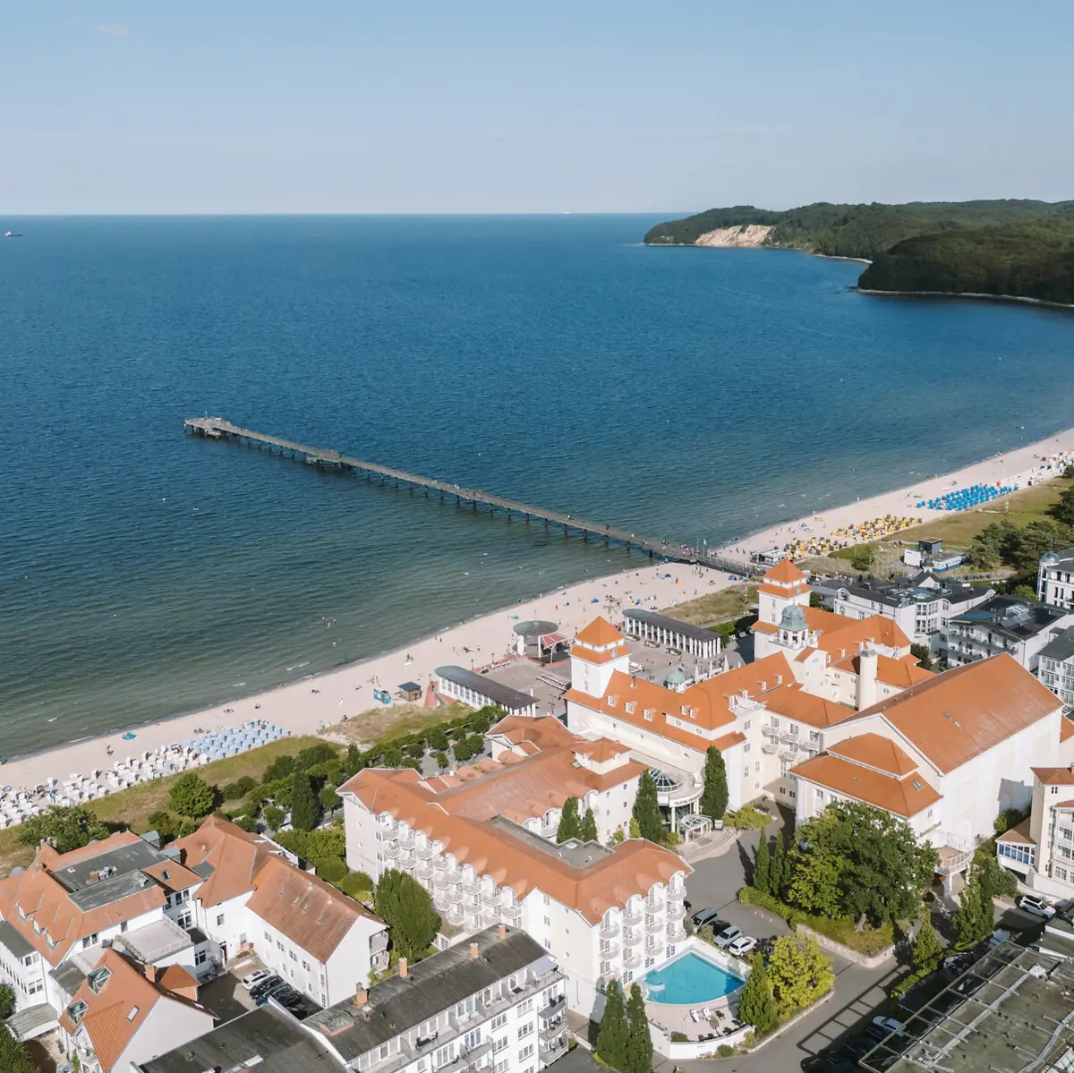 Strand mit Gebäuden und einem Pier aus der Vogelperspektive.