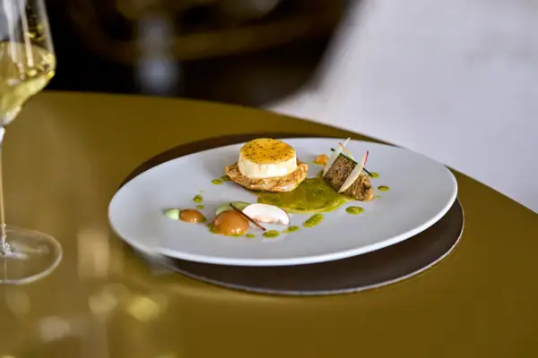 Kilian Stuba Ein Teller mit exquisit angerichteten Essen auf einem Tisch.