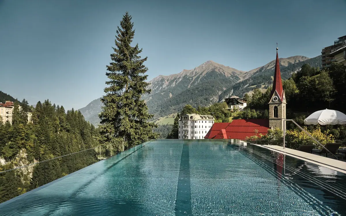 Ein Pool mit einem Gebäude und Bergen im Hintergrund.