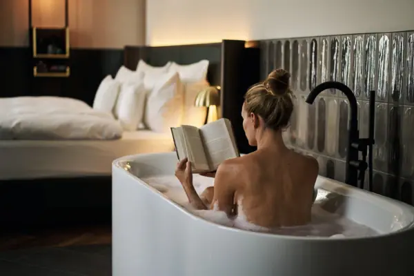 Eine Frau in einer Badewanne liest ein Buch.