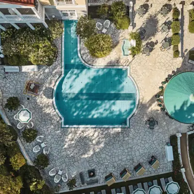 Pool mit Stühlen und Bäumen im Freien.