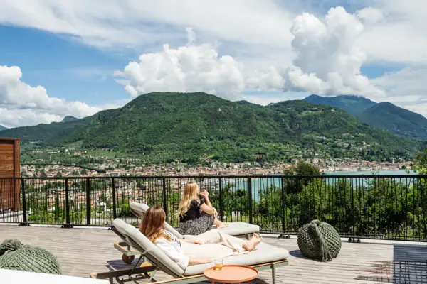 Zwei Frauen sitzen auf einem Deck mit Blick auf ein Gewässer.