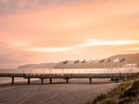 Brücke mit Flaggen bei Abenddämmerung, umgeben von Wasser und leicht bewölktem Himmel.