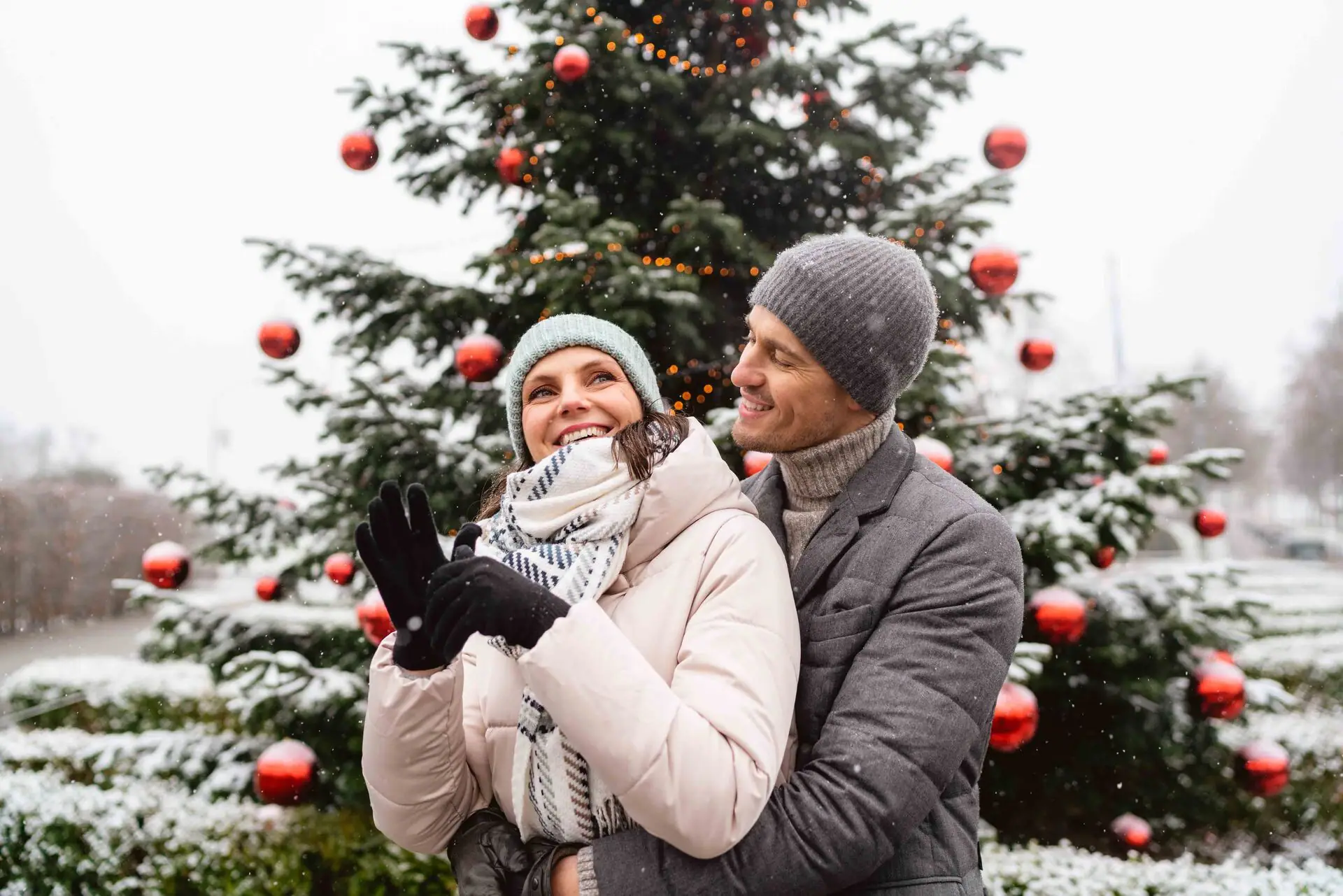 Ein Mann und eine Frau stehen vor einem Weihnachtsbaum.
