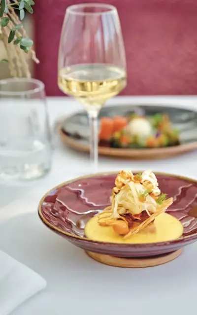 Ein Teller mit Essen auf einem Tisch, umgeben von Weingläsern und Besteck.