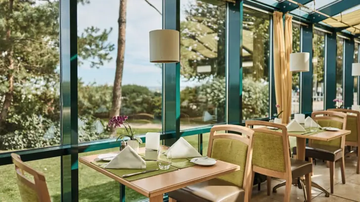 Ein Tisch mit Stühlen und Servietten in einem Raum mit Fenstern.
