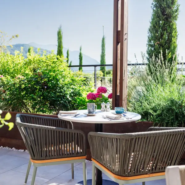 Un tavolo per la colazione al sole del mattino con fiori rosa e una vista sul paesaggio verde