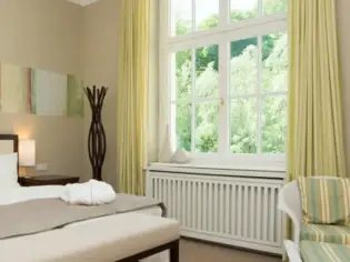 Ein helles Hotelzimmer mit einem großen Bett und einem grünen Sessel.