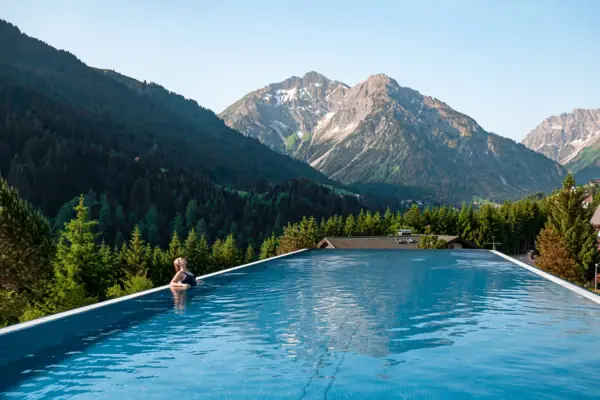 Wellnesshotel Österreich Eine Person in einem Pool mit Bergen im Hintergrund.