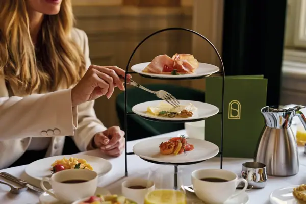 Eine Person hält eine Gabel über einer Etagere beim Frühstück im Straubinger Grand Hotel Bad Gastein..