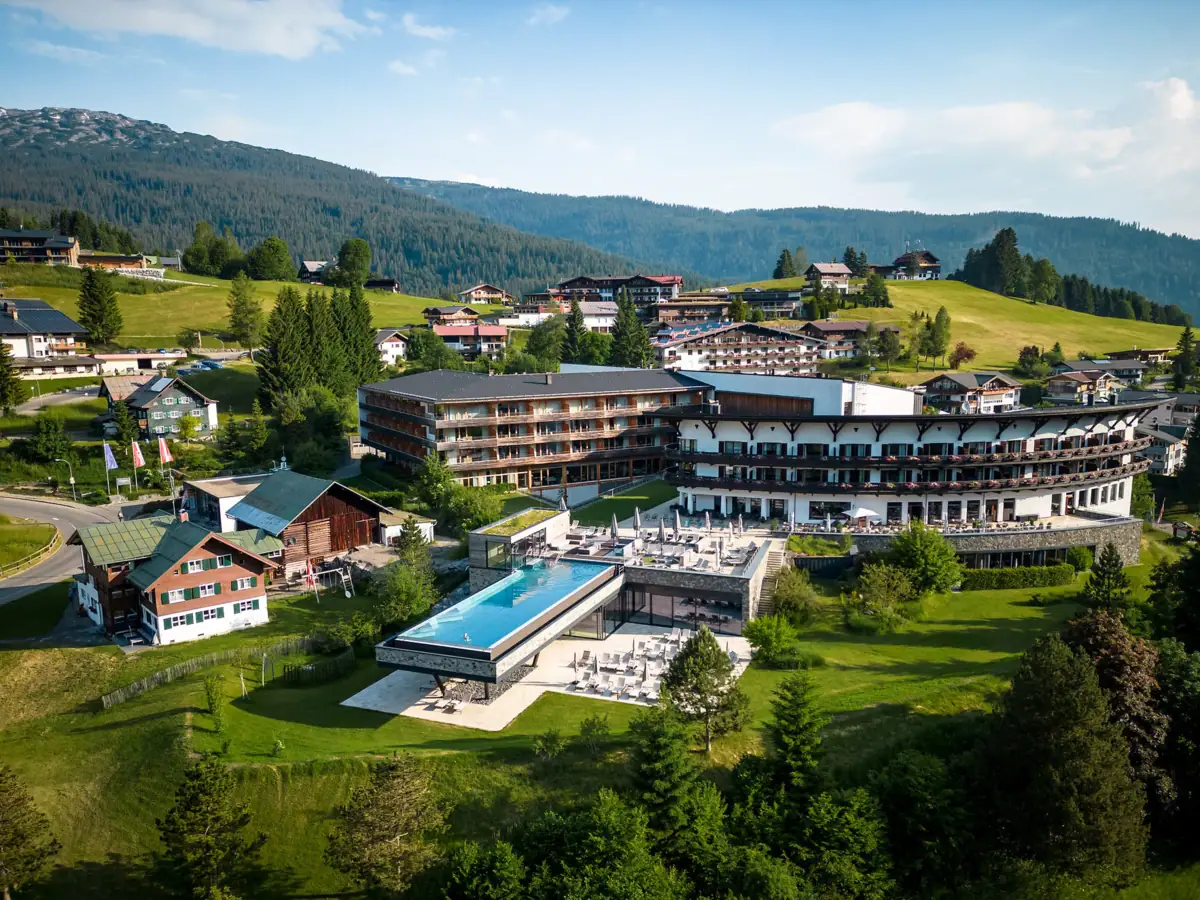 Das A-ROSA Ifen Hotel Kleinwalsertal mit Pool inmitten einer malerischen Berglandschaft.