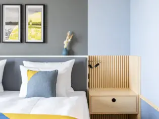 Detailaufnahmevvon einem Hotelbett mit blauen und gelben Akzenten.