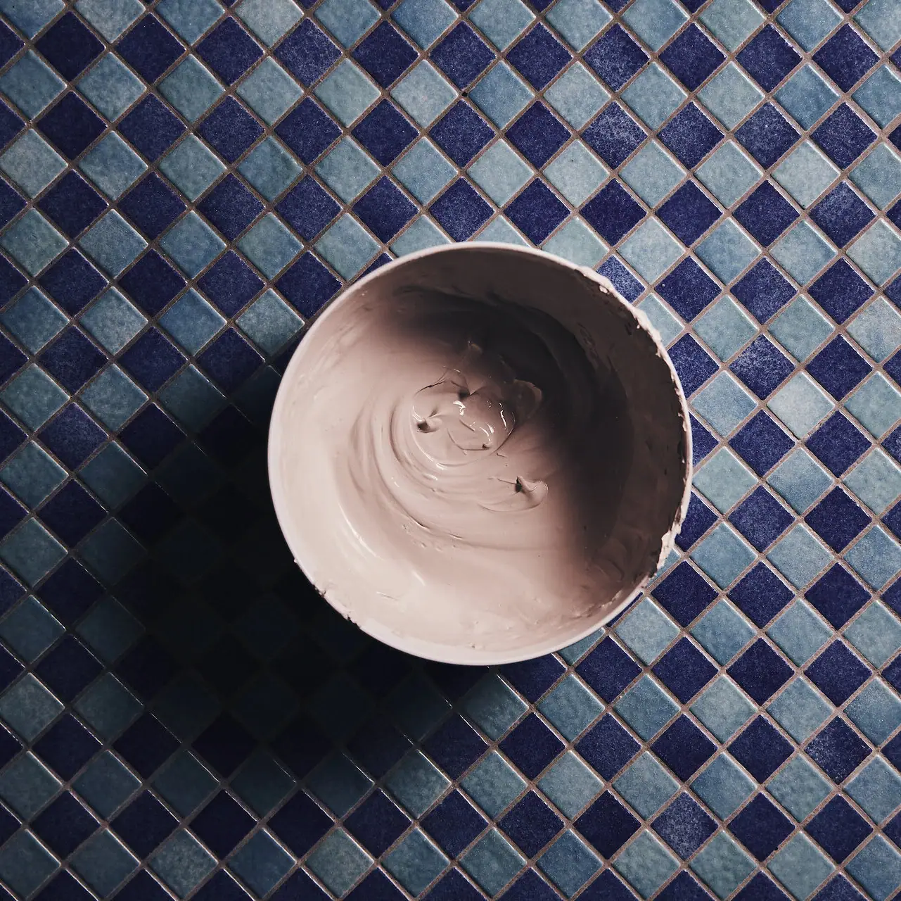 Eine Schale mit beiger Paste auf einem blauen Fliesenmosaik