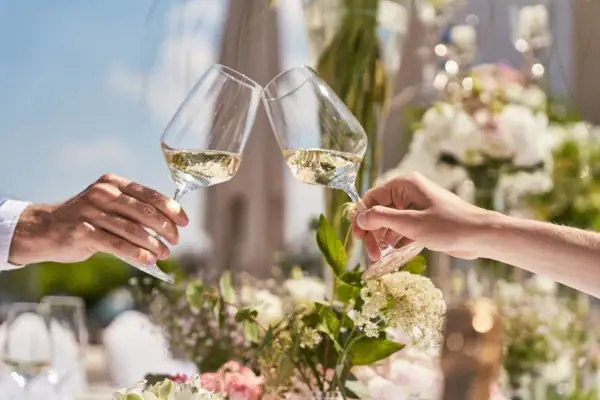 Zwei Hände stoßen mit Weingläsern an.