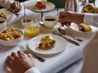 Ein Frühstückstisch mit Obstsalat und Eierspeisen sowie Kaffee und Orangensaft.