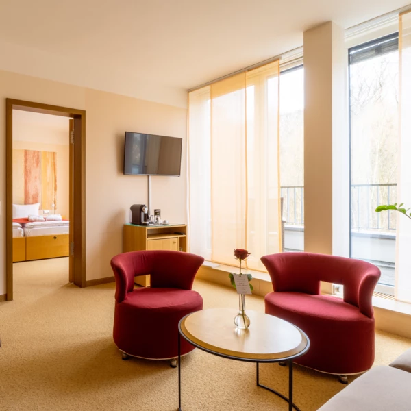 A room with red chairs and a television, featuring a coffee table and modern interior design elements.