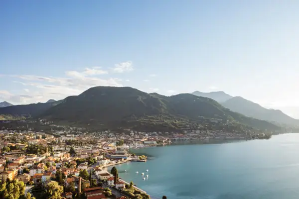Luftaufnahme des Gardasees mit Blick auf die Stadt Salò und die umliegenden Berge.