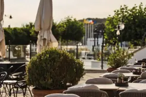 Tische und Stühle im Freien mit Bäumen und einer Straße im Hintergrund.