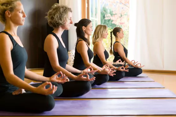 Fünf Frauen sitzen im Meditationssitz auf Yogamatten