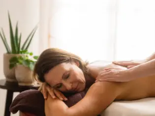 Frau liegt auf einer Massageliege in einem Raum mit Zimmerpflanzen.