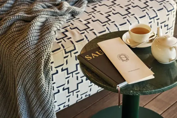Ein Tisch mit einem Buch und einer Tasse Tee darauf.