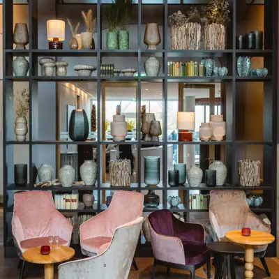 Ein Zimmer mit einem Regal voller Vasen und Stühlen.
