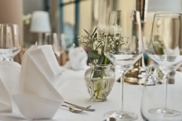 Elegant gedeckter Tisch mit Weingläsern und einer Vase mit Blumen.