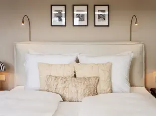 A cozy hotel bedroom featuring a neatly made bed with plush pillows and elegant bedside lamps.