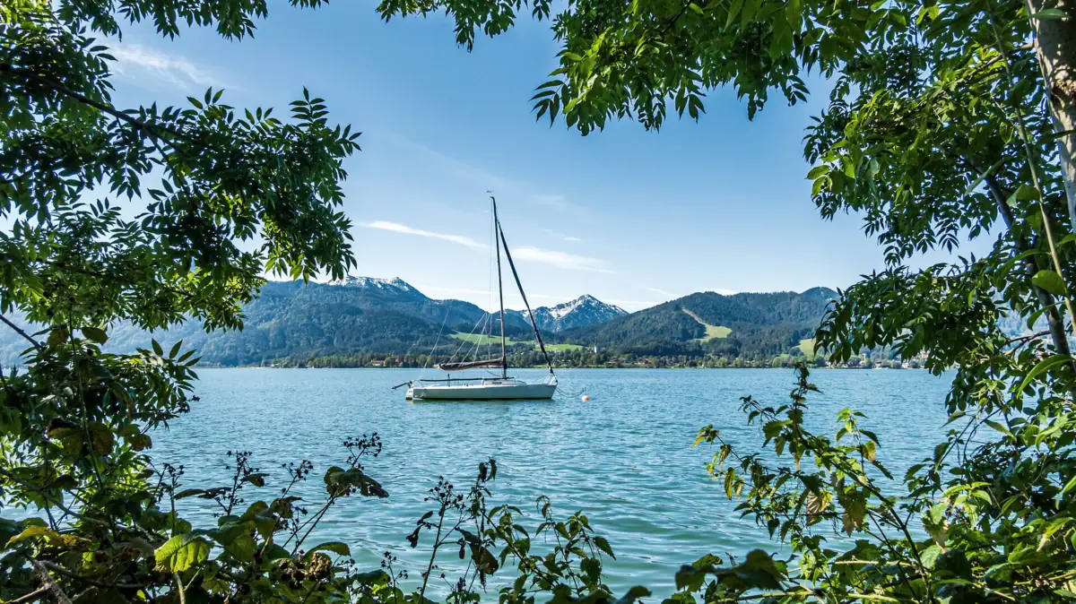 Ein Boot auf dem Tegernsee mit Bergen im Hintergrund.