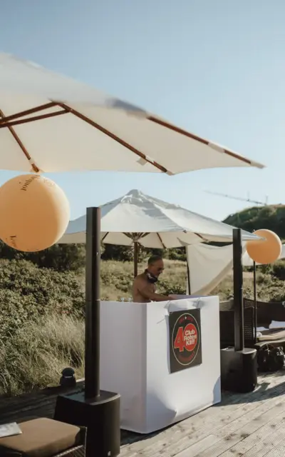 Ein DJ spielt entspannte Musik unter Sonnenschirmen auf einer Terrasse, die mit Veuve Clicquot Luftballons dekoriert ist.