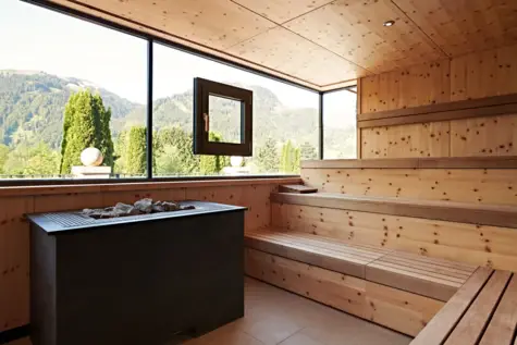 Sauna aus Holz mit Fensterblick auf Berge.