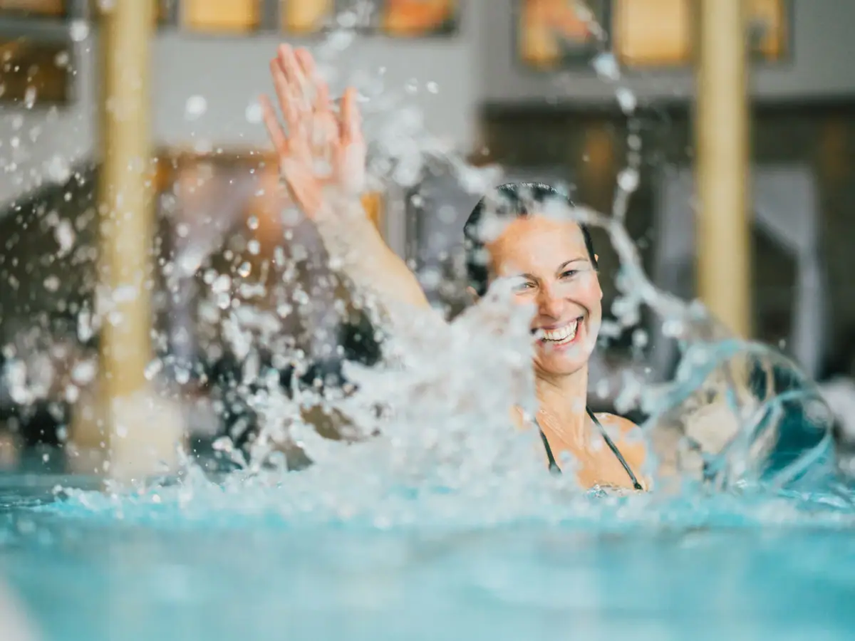 Eine Frau in einem Pool mit spritzendem Wasser.