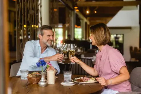 Ein Mann und eine Frau sitzen an einem Tisch im Restaurant und halten Weingläser.