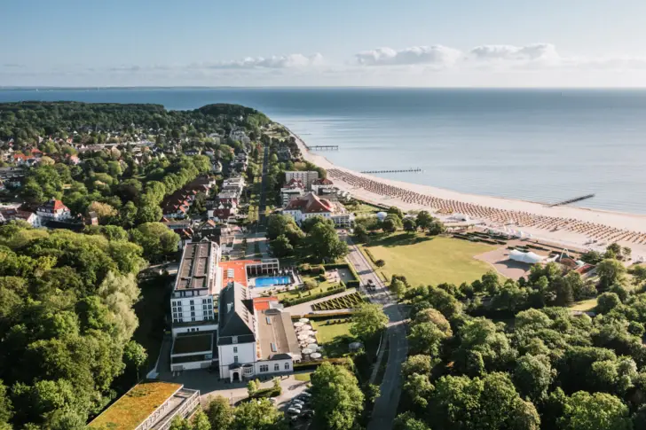 Luftaufnahme einer Stadt am Strand mit Gebäuden umgeben von Bäumen und Wasser.