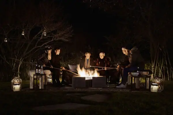 Eine Gruppe von Menschen um eine Feuerstelle im Freien.