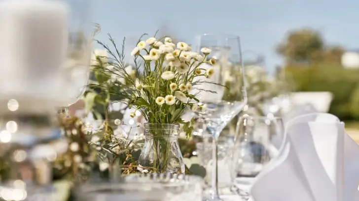 Elegant gedeckter Tisch mit Blumenarrangement und Gläsern.