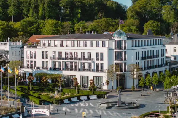 Weißes Gebäude mit Bäumen im Hintergrund.