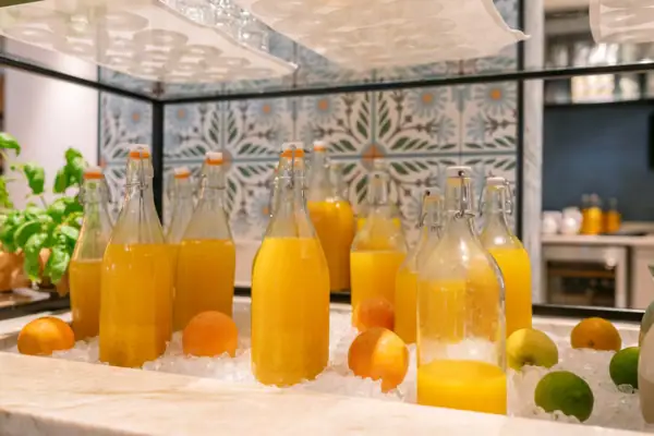 Eine Gruppe von Flaschen mit Orangensaft und Obst auf Eis.