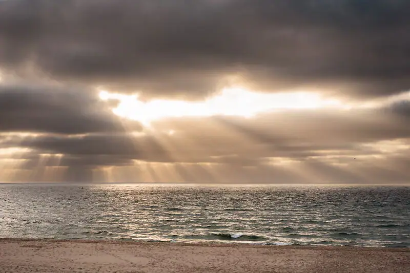 Sonne scheint durch die Wolken über dem Ozean.
