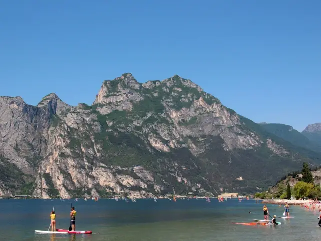 Personen auf Stand Up Paddel Boards auf einem See, umgeben von Bergen.