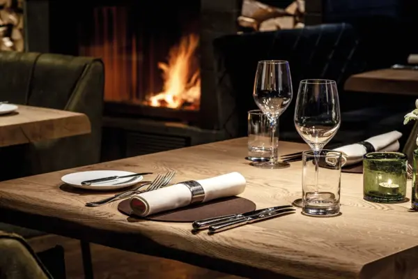 A table with a napkin and glasses on it with a fire in the background.