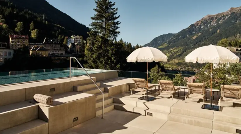 Ein Pool mit Sonnenschirmen und Liegestühlen an einem sonnigen Tag.