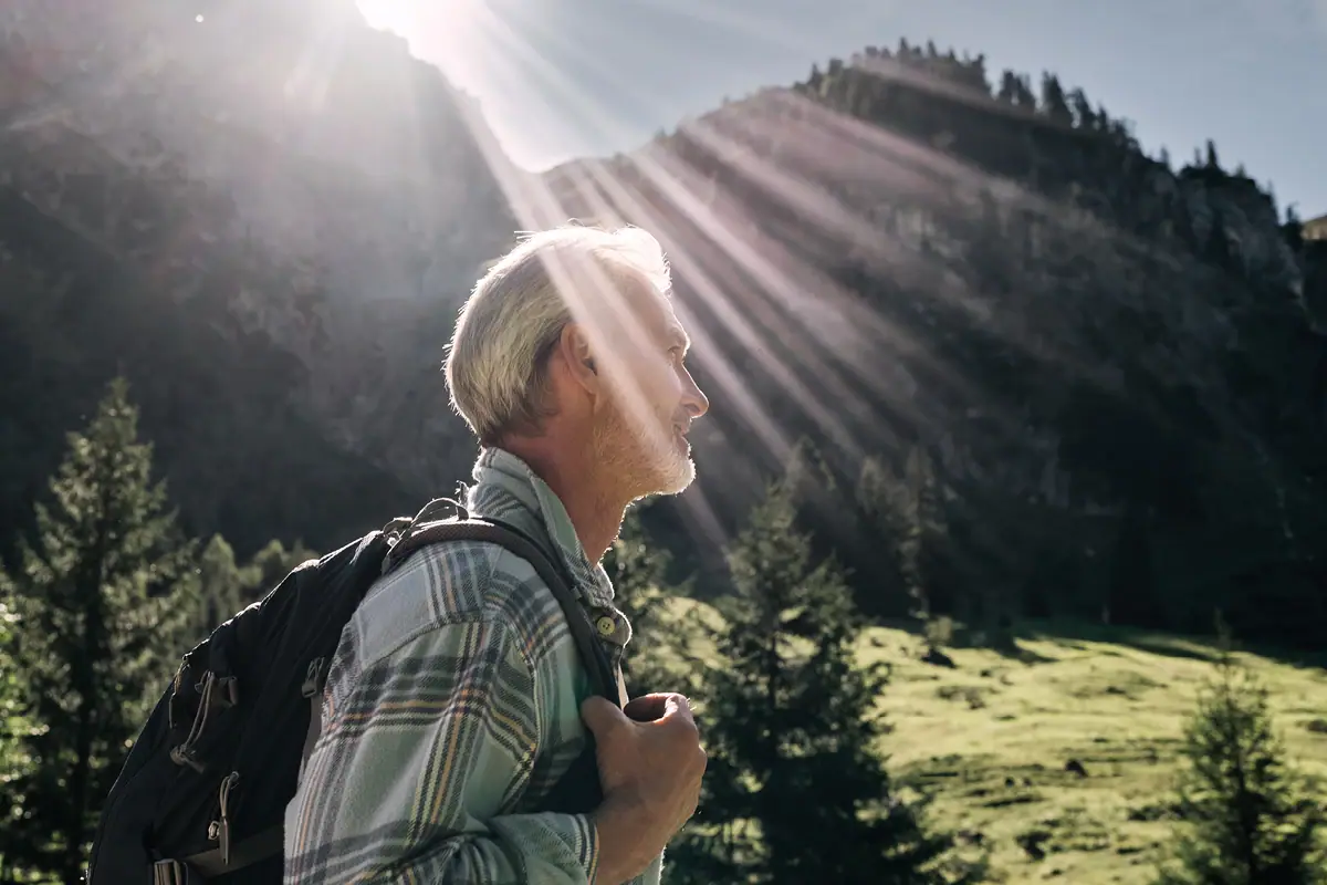 Ein Mann mit Rucksack steht vor einem Berg.