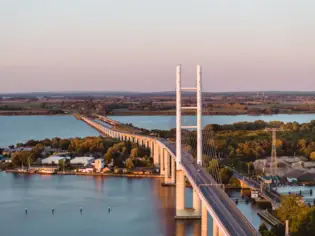 Brücke über einem Gewässer mit einer Straße und Bäumen umgeben.