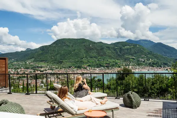 Zwei Frauen sitzen auf einem Deck mit Blick auf ein Gewässer.