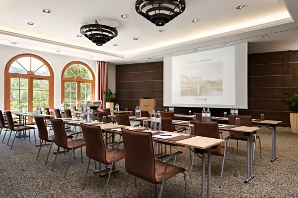 Ein Raum mit Tischen, Stühlen und einer Projektionsleinwand.