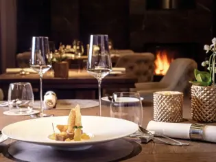 A table with a plate of food and wine glasses in an interior.